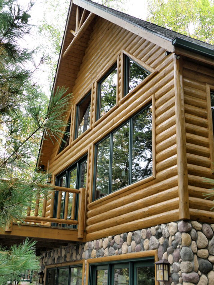 Half log hewn siding with a cedar railing around the deck