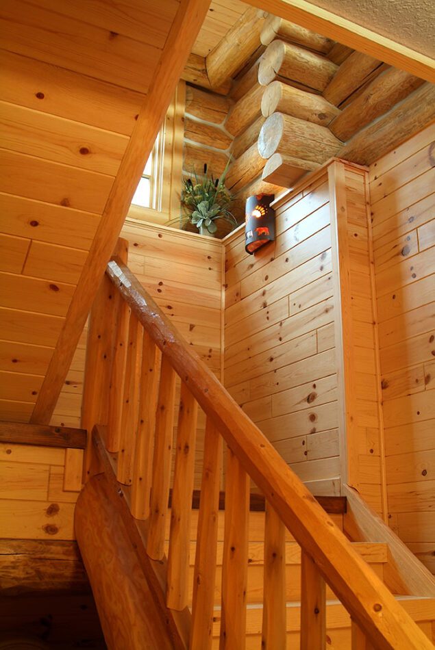 Staircase with cedar railing and knotty pine paneling